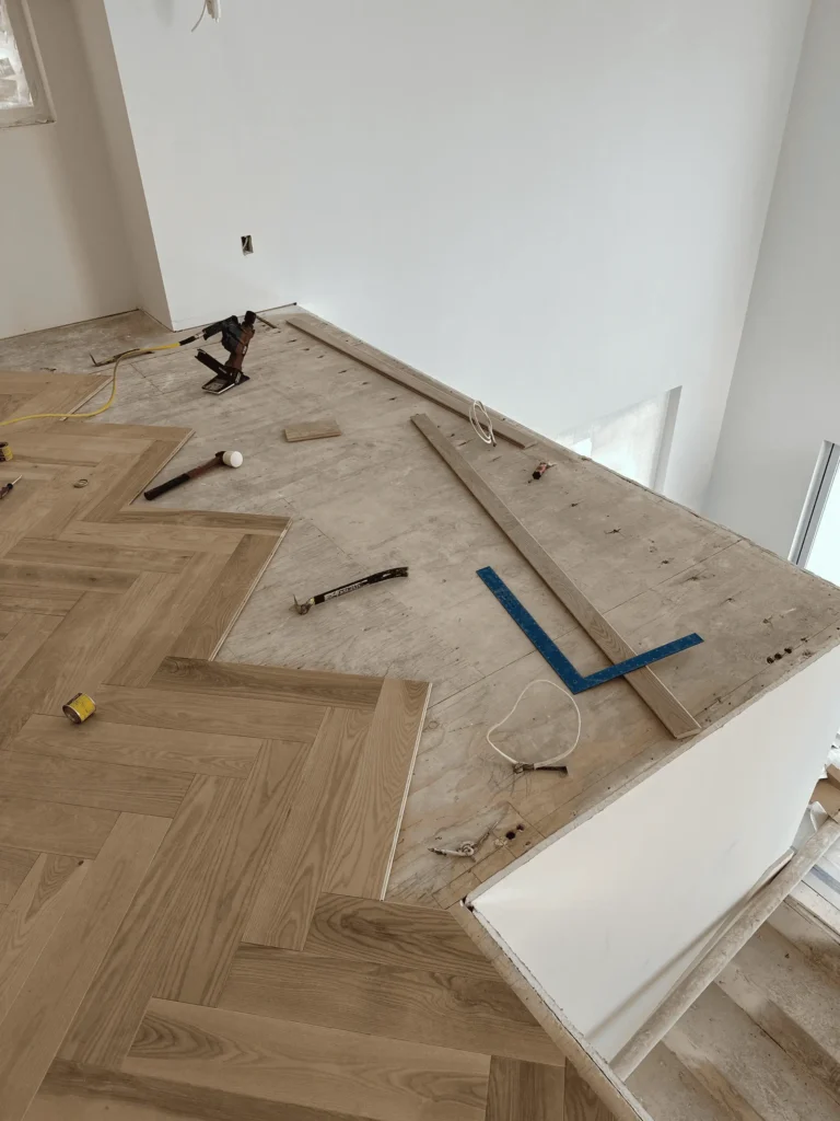 Partially installed wood flooring with tools and materials scattered around.