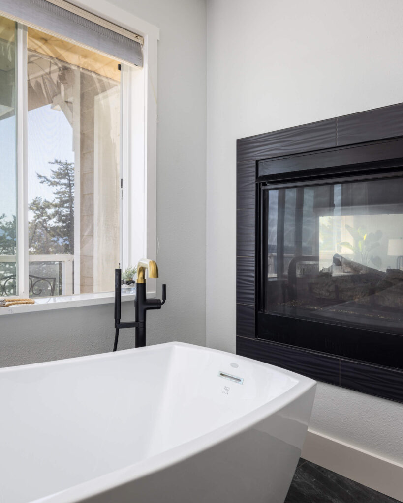 The white bathtub next to a fireplace.