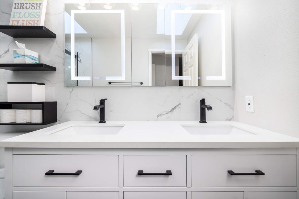 Modern double vanity with illuminated mirrors in bathroom.