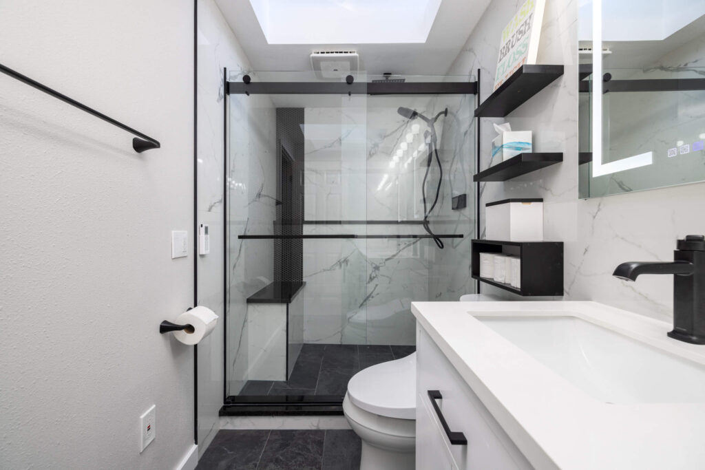 Modern bathroom with glass shower enclosure and marble tiles.